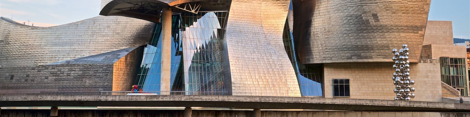 Guggenheim Museum Bilbao which includes modern architecture, a sunset and a river or creek
