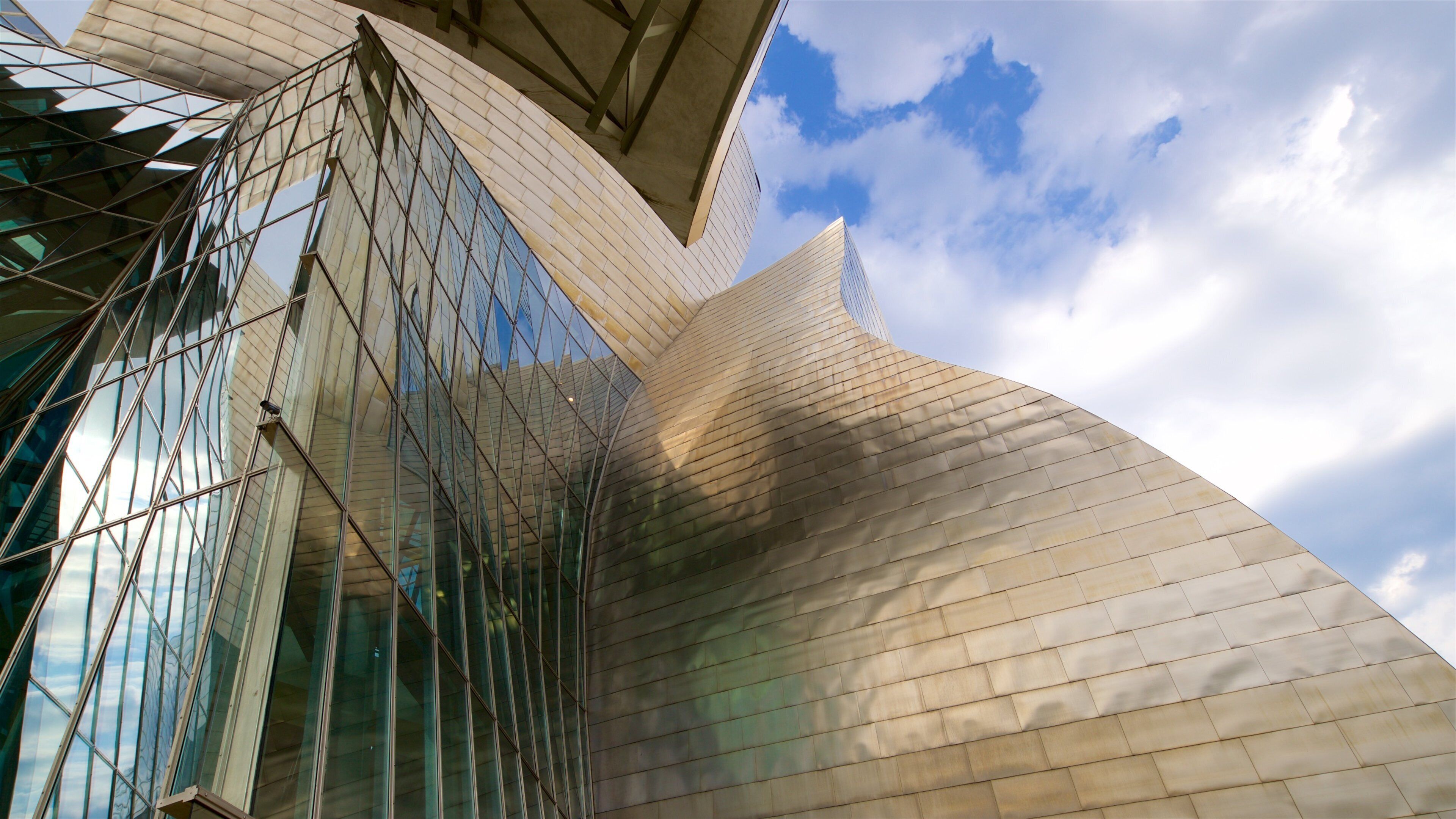 A modern architectural structure with reflective glass and a curved facade.