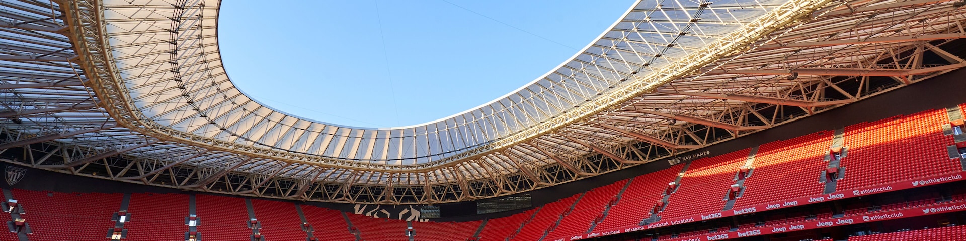 Un estadio grande con techo circular y asientos rojos.