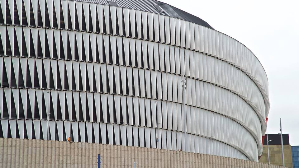 A modern architectural building with a curved facade and a series of vertical panels.