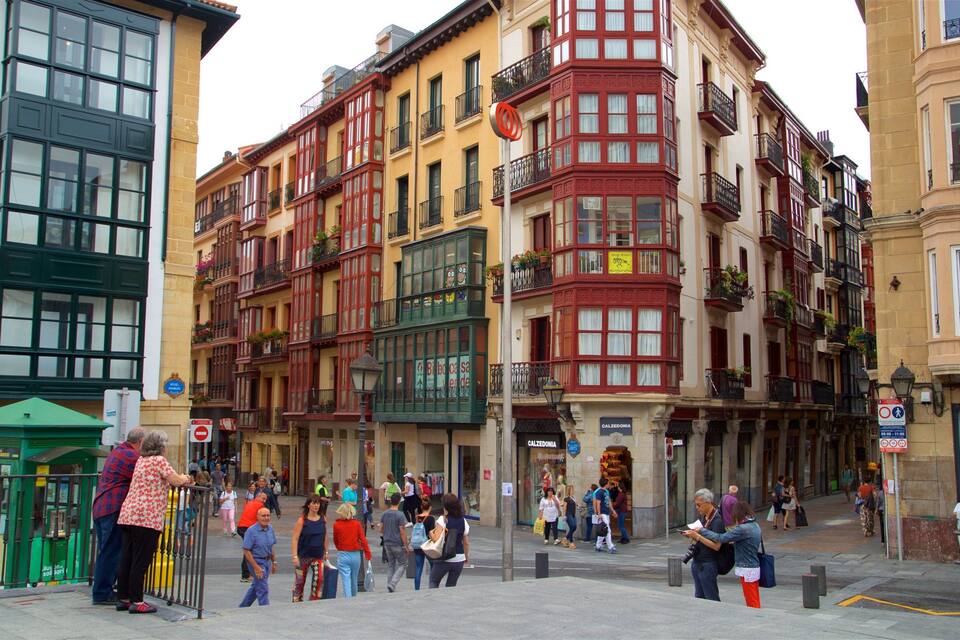 A bustling street with colorful buildings, a green bus stop, and pedestrians.