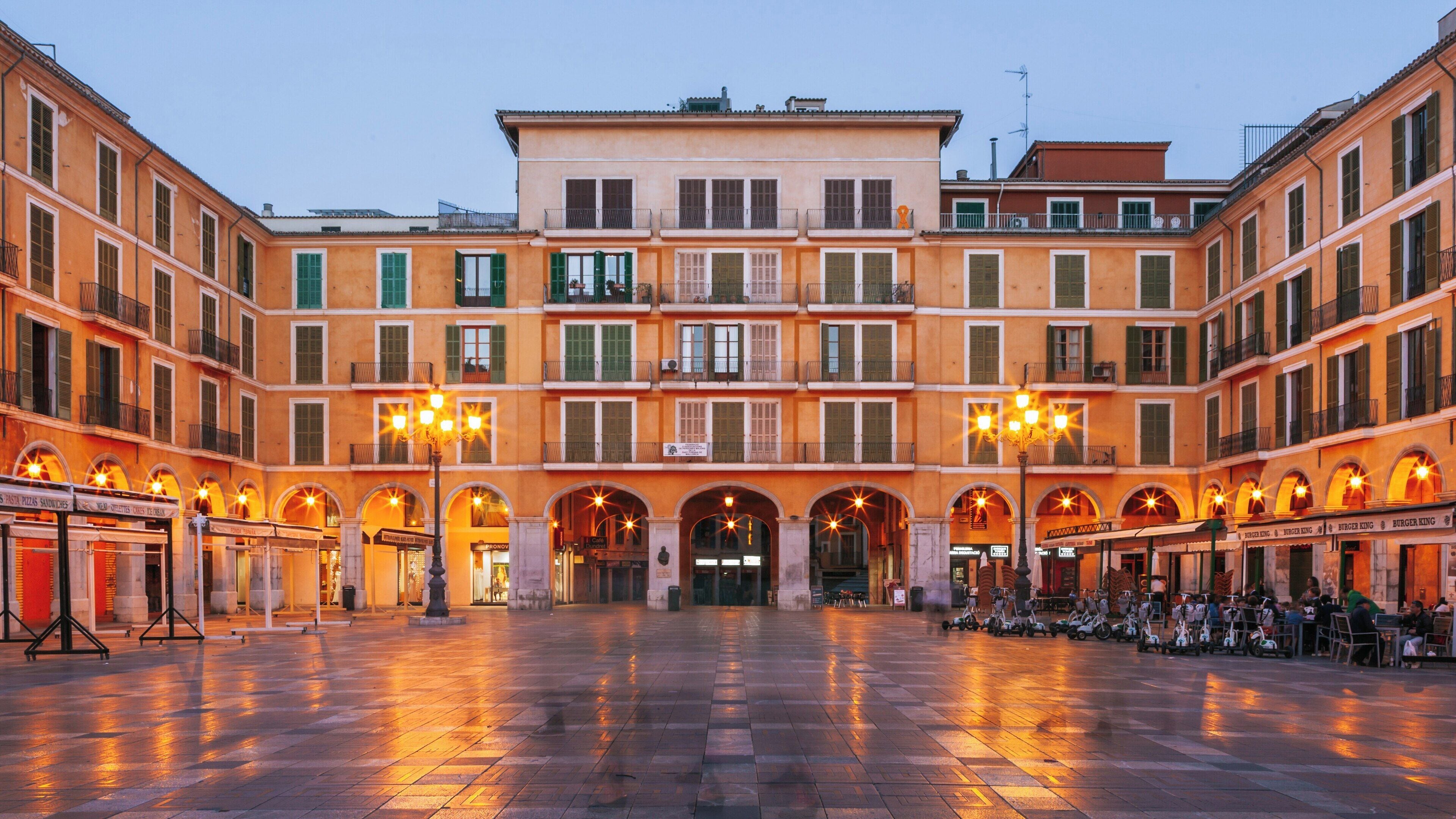 Vibrant evening atmosphere in Plaza Mayor de Palma, showcasing historic architecture in Palma de Mallorca Old Town, Balearic Islands, Spain