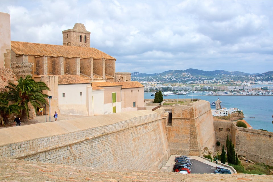 A coastal city with historic buildings, a fortified wall, and a harbor with boats.