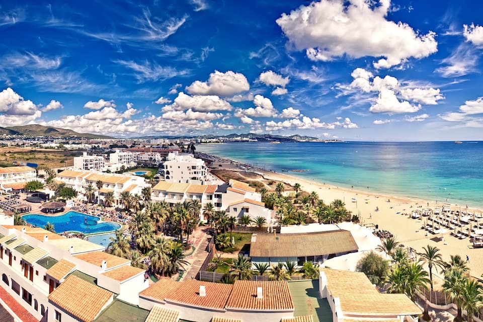 A coastal resort with a beach, swimming pool, and palm trees.