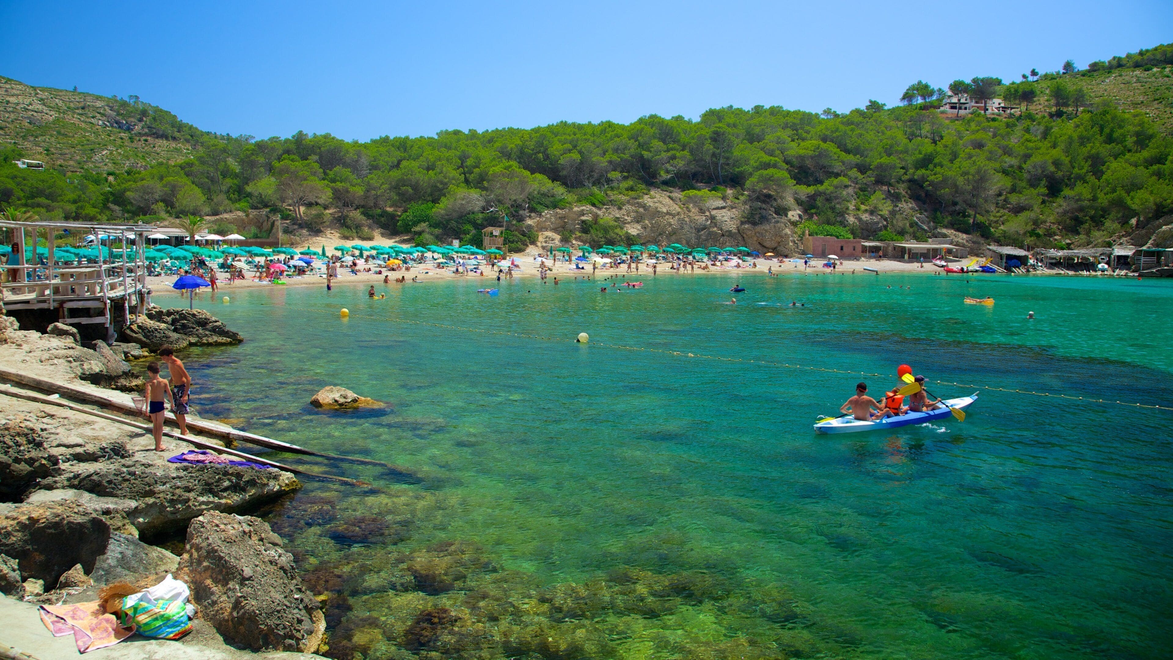 Benirràs strand som inkluderer strand med småstein, korallrev og kajakkpadling eller kanopadling