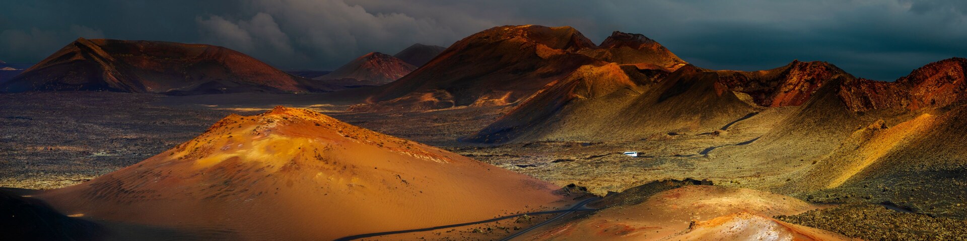 Wüstenlandschaft mit markanten Sanddünen und felsigen Bergen unter einem beeindruckenden Himmel.