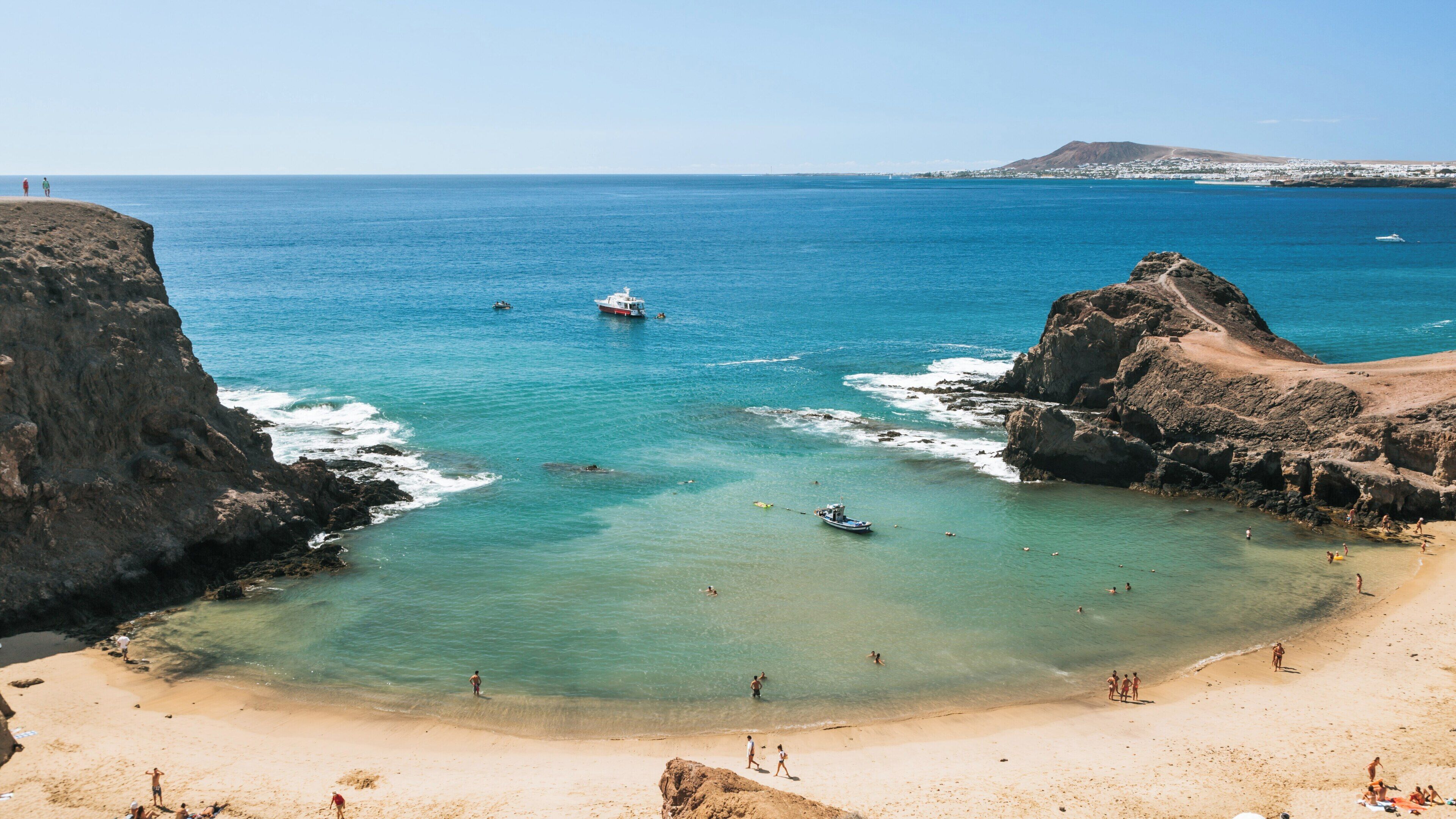 Relaxing day at Papagayo Beach in Yaiza, Canary Islands, featuring clear waters and sandy shores under bright blue skies