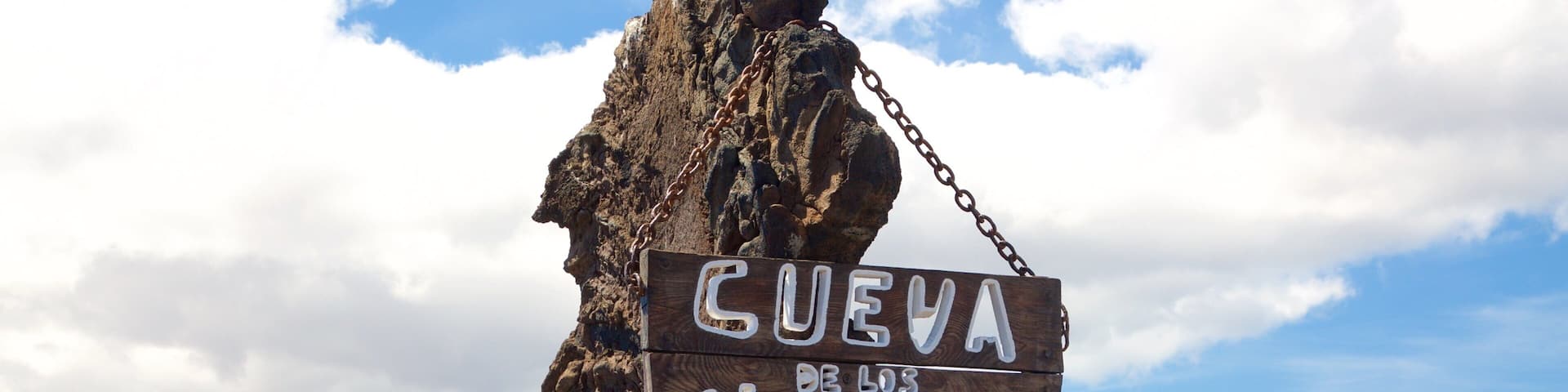 A large rock formation with a sign reading "Cueva de los Verdes".
