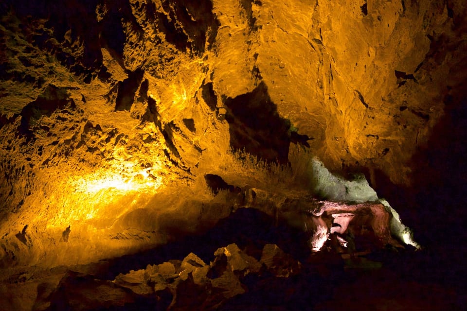 A cave with illuminated rock formations and a stream.