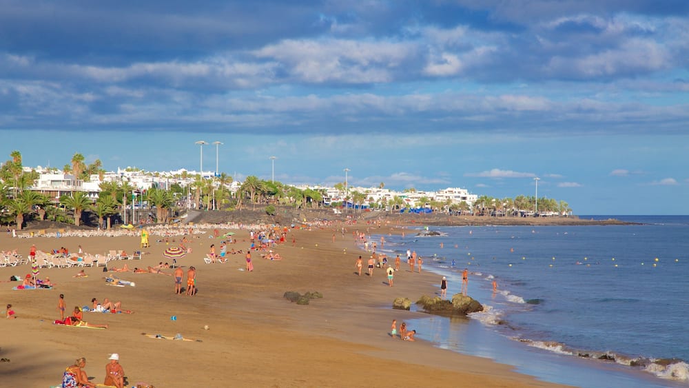 Puerto del Carmen Beach showing general coastal views and a beach as well as a large group of people