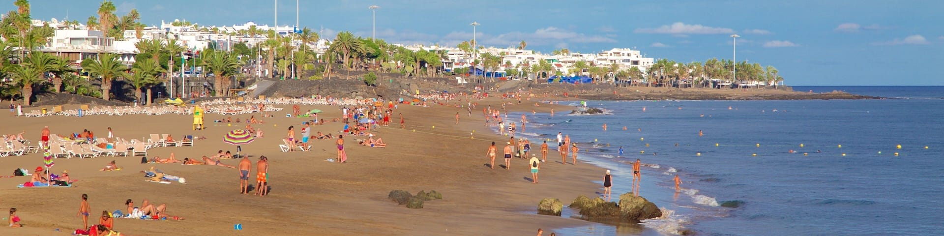 Puerto del Carmen Beach showing general coastal views and a beach as well as a large group of people