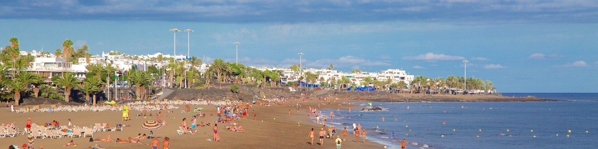 Puerto del Carmen Beach showing general coastal views and a beach as well as a large group of people
