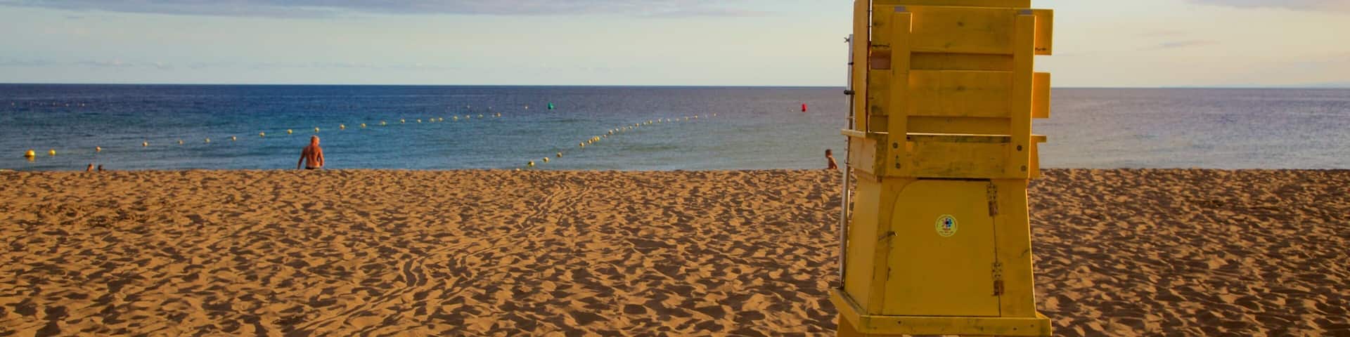 Puerto del Carmen Beach which includes a sunset, general coastal views and a sandy beach