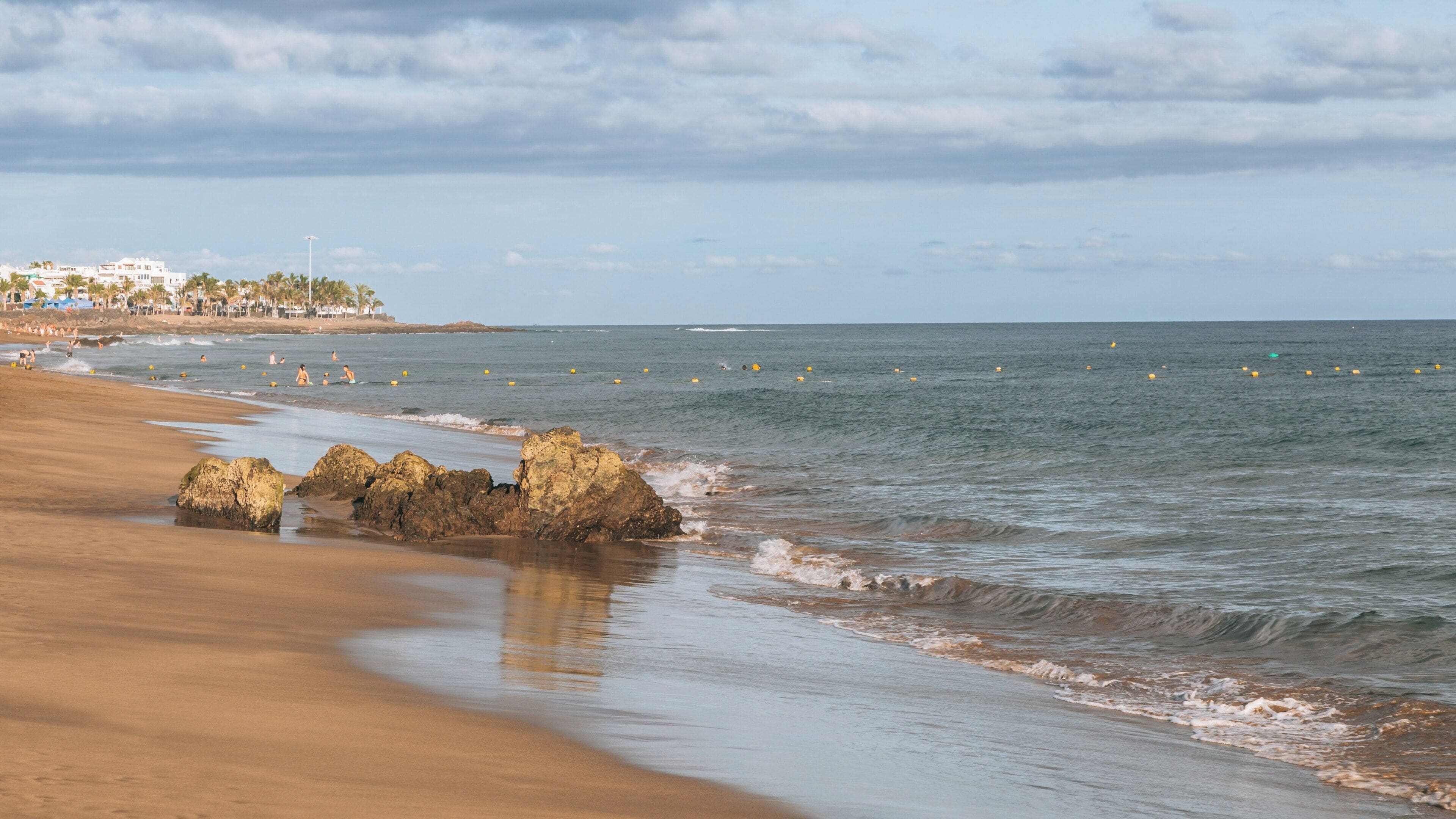 Stunning view of Puerto del Carmen Beach in Tías, Canary Islands with golden sand and gentle waves under a clear blue sky