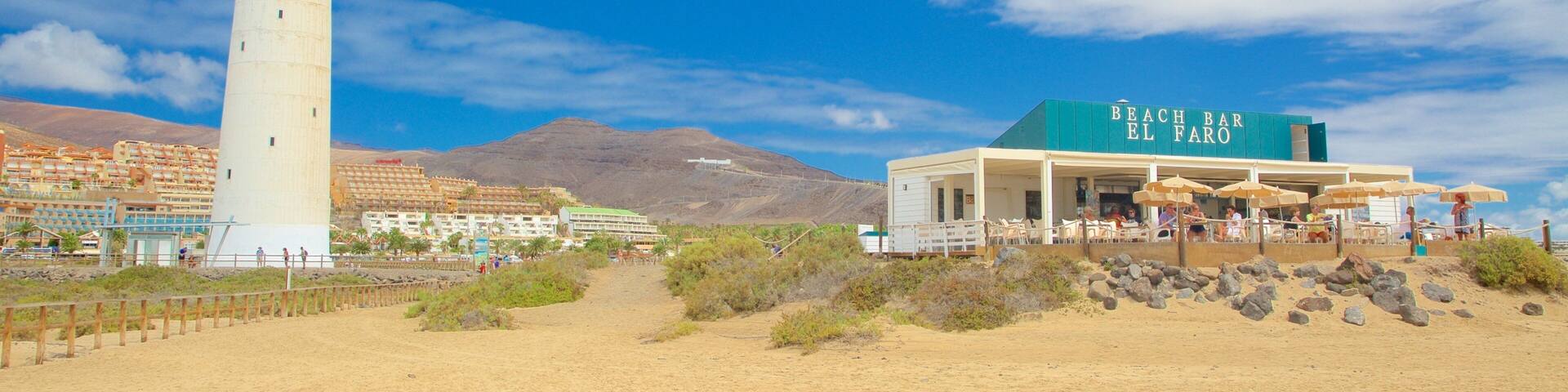 A lighthouse, Beach Bar El Faro, and a desert landscape with mountains in the background.