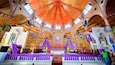 A church interior with a vibrant, ornate ceiling, stained glass windows, and a central altar.