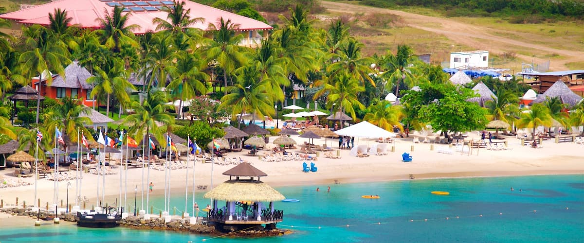 A tropical beach with clear turquoise waters, palm trees, and beach umbrellas.
