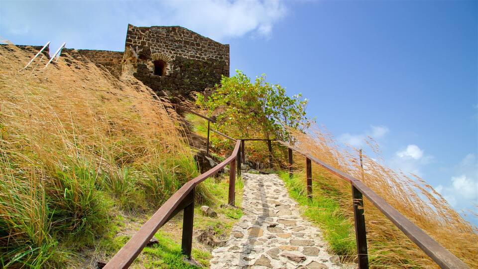 A stone staircase leading up a hill with a stone wall and a metal railing.