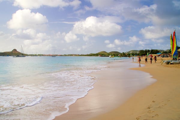 A beach with a sandy shore, calm water, and sailboats.
