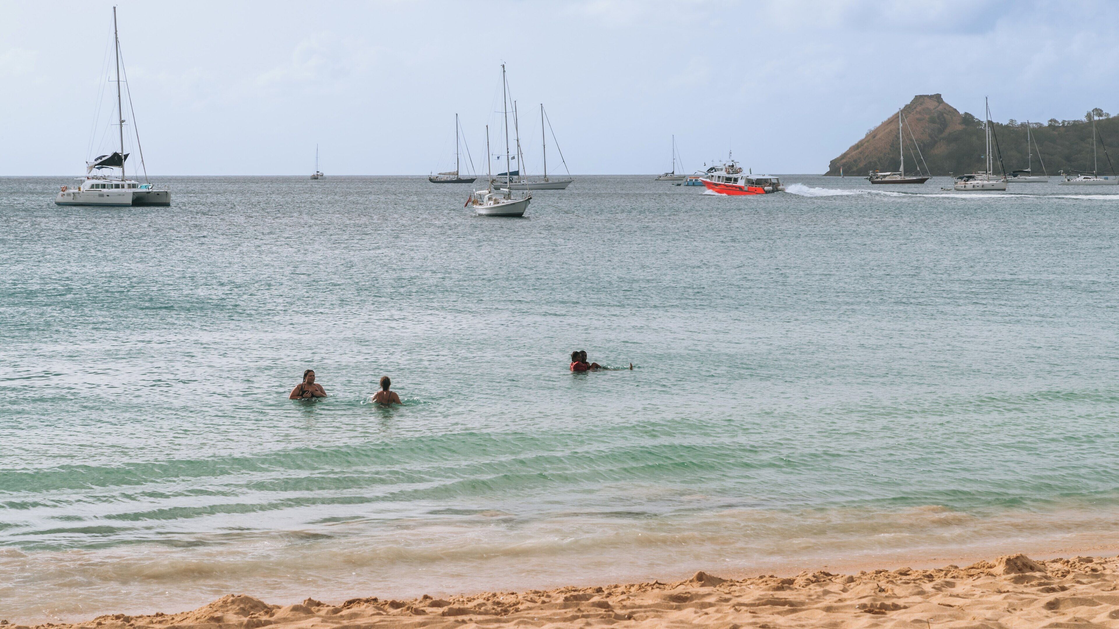 Relaxation and leisure activities at Reduit Beach in Gros Islet, St. Lucia with calm waters and sailing boats in the background during a sunny day