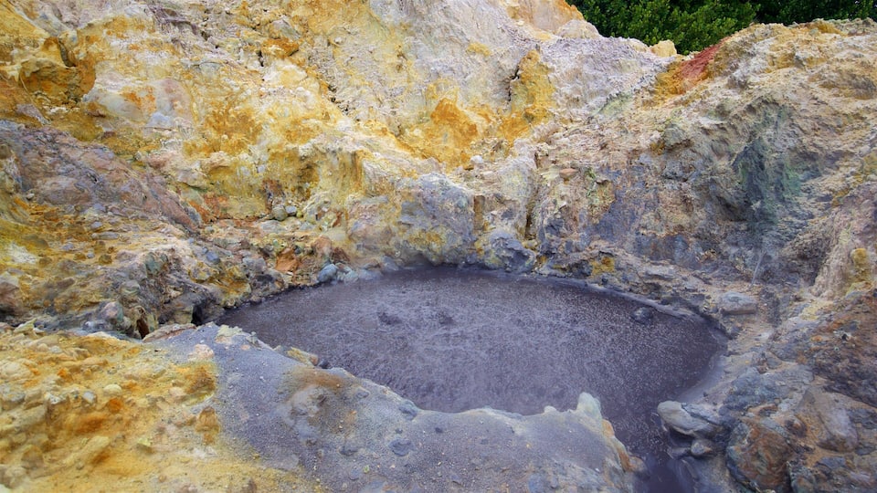 A volcanic crater with a dark central area surrounded by colorful, eroded rock formations.