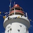 A lighthouse with a red top and white base, adorned with colorful flags.