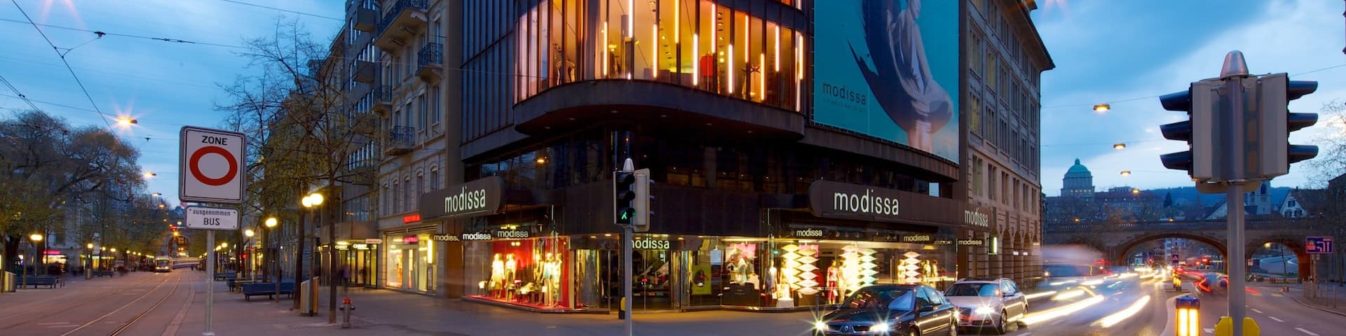A modern building with illuminated windows and a large billboard.
