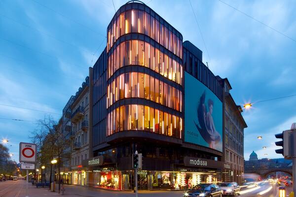 A modern building with illuminated windows and a large billboard.