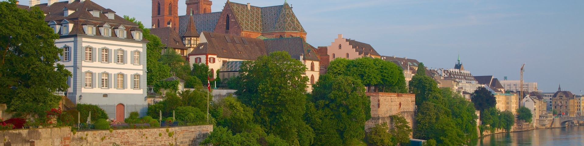A historic cityscape with a prominent cathedral, a river, and lush greenery along the riverbank.