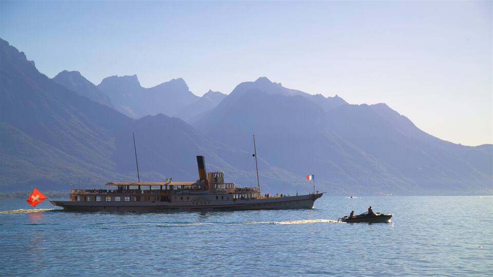 A boat on a calm lake with mountains in the background.