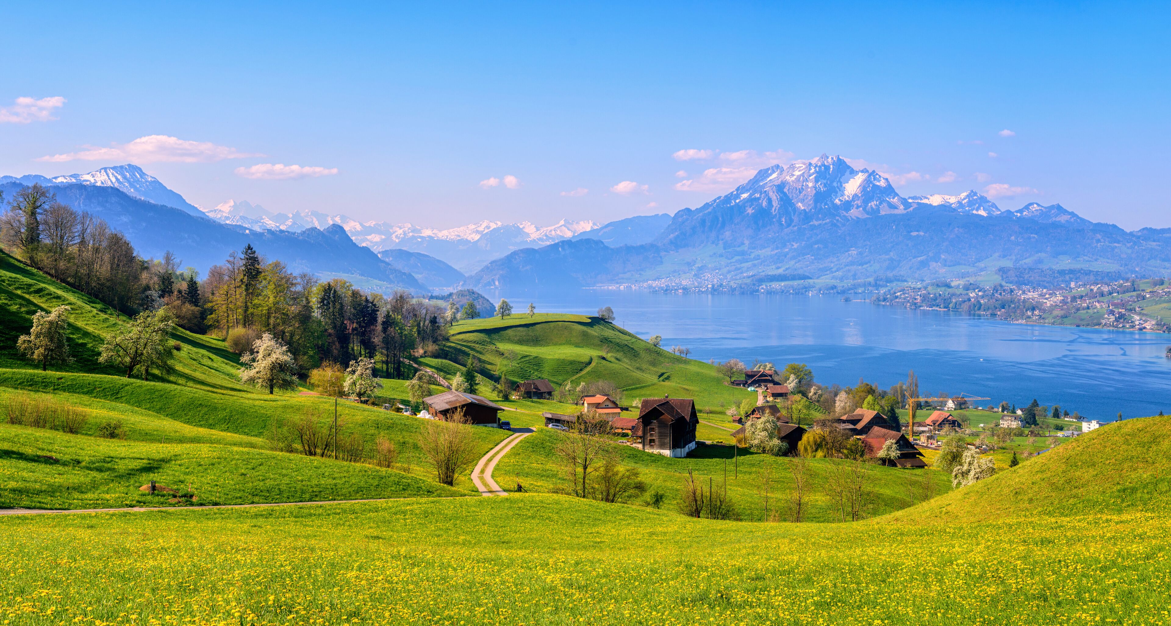 A mountainous landscape with a lake, green fields, and traditional houses.
