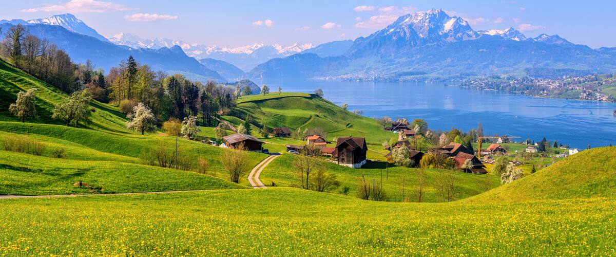 A mountainous landscape with a lake, green fields, and traditional houses.