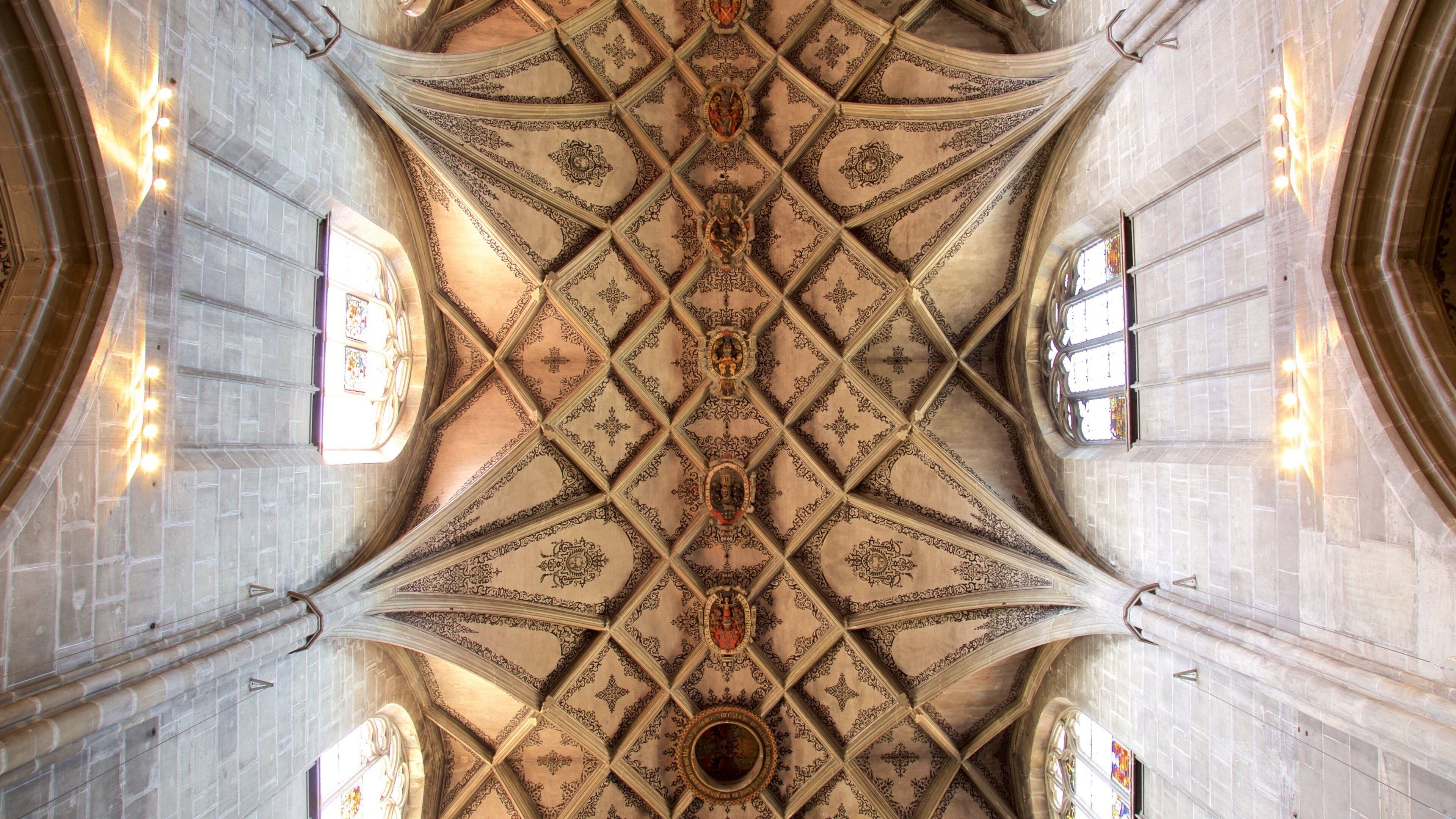 A cathedral ceiling with intricate geometric patterns and stained glass windows.