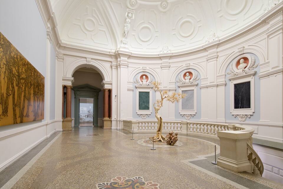 Upea aula, jossa on koristeellinen katto, klassiset pylväät ja suuri maalaus.