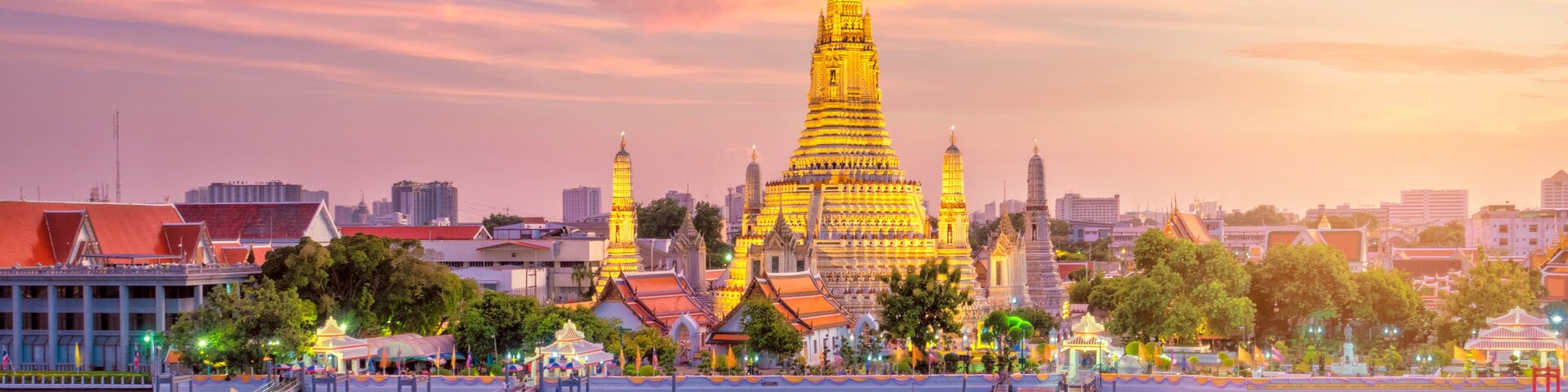 Una pagoda dorada reflejada en aguas tranquilas, rodeada de edificios y árboles de la ciudad.