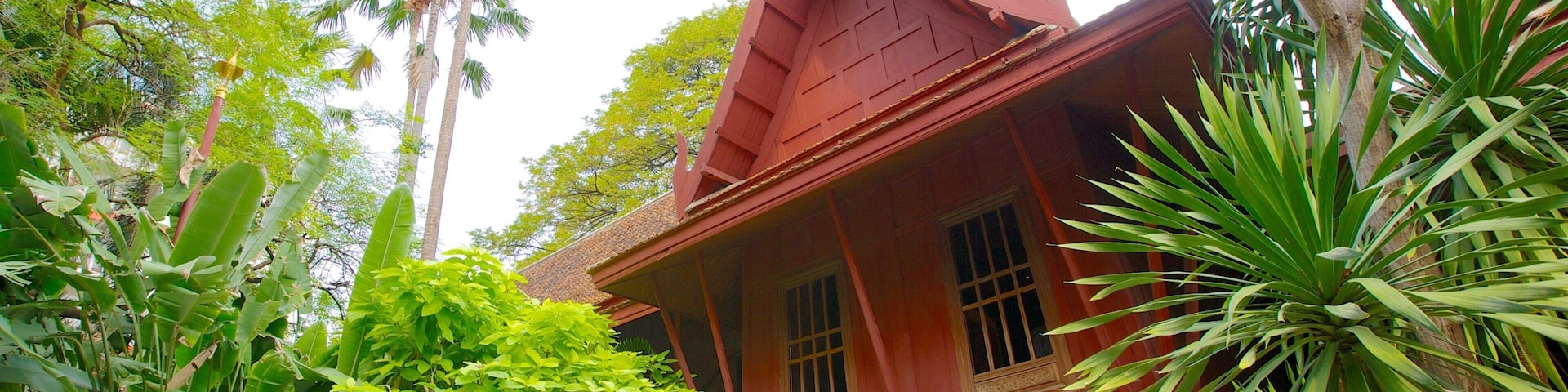 Uma casa tradicional vermelha cercada por vegetação exuberante e árvores altas.