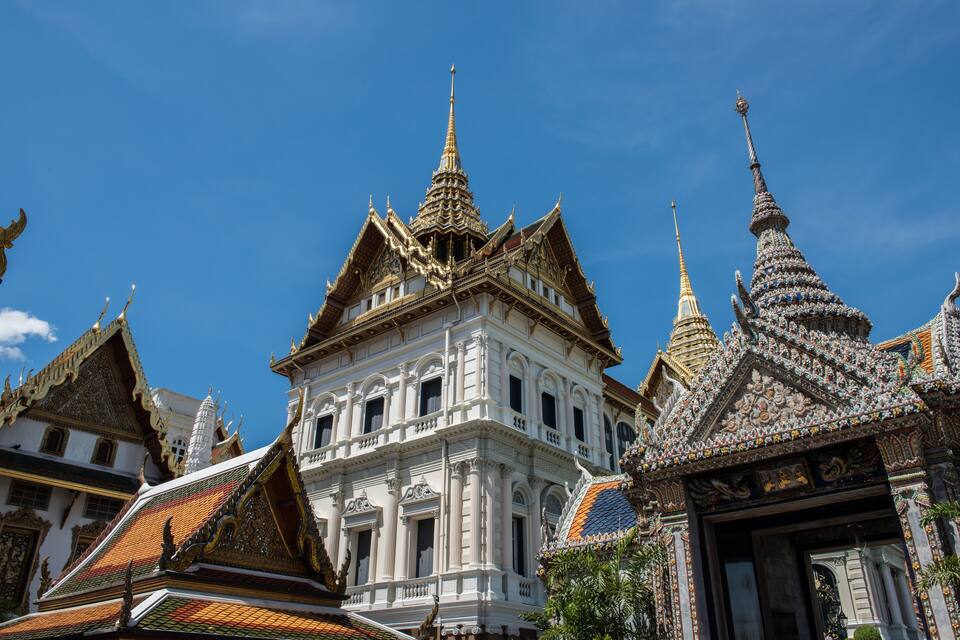 A white temple with ornate golden spires and a tiled roof.