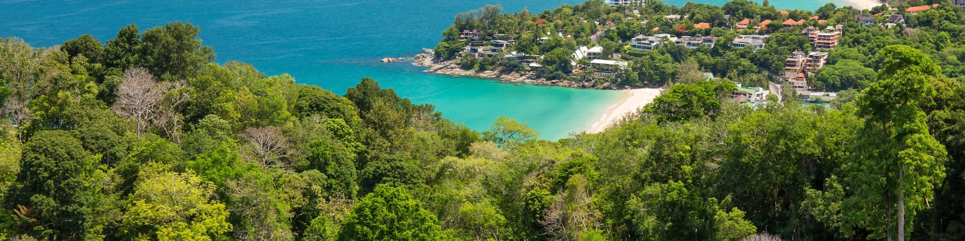 A coastal landscape with turquoise waters, a sandy beach, and lush greenery.
