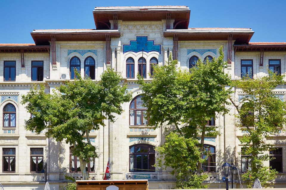 Un bâtiment historique à l’architecture riche et élaborée, doté de grandes fenêtres et d’une croix bleue bien visible.