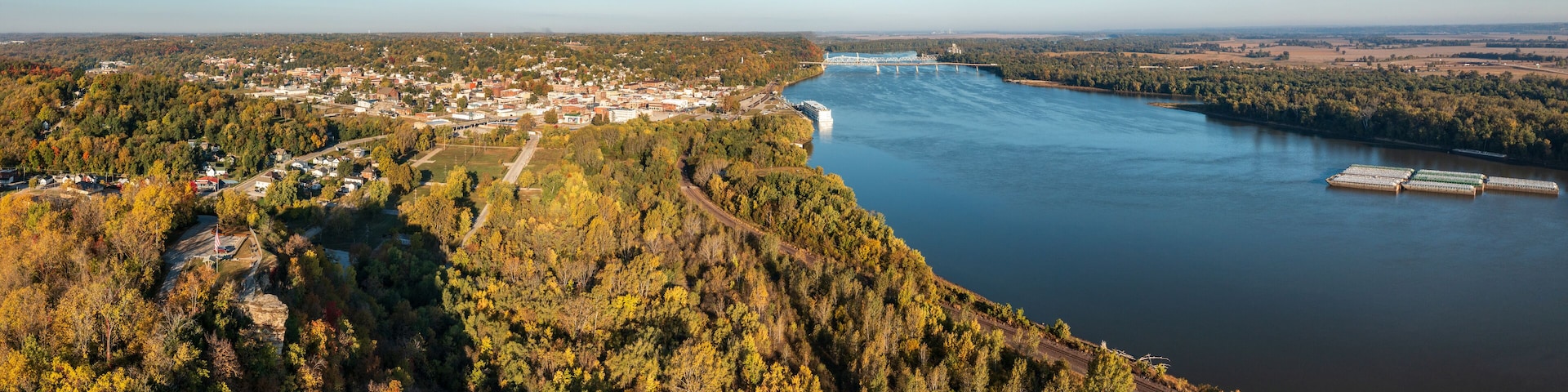 A river with a bridge, a town, and a forested hillside.