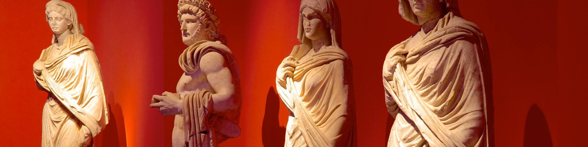 Tres estatuas de mármol clásico sobre un fondo rojo.