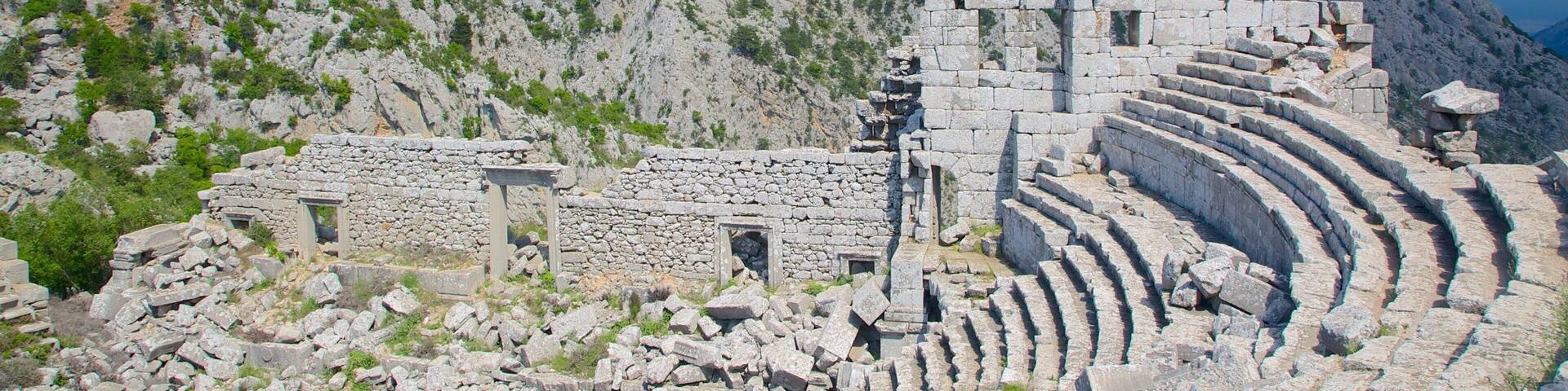 Ancient ruins with stone steps and walls, set against a mountainous backdrop.