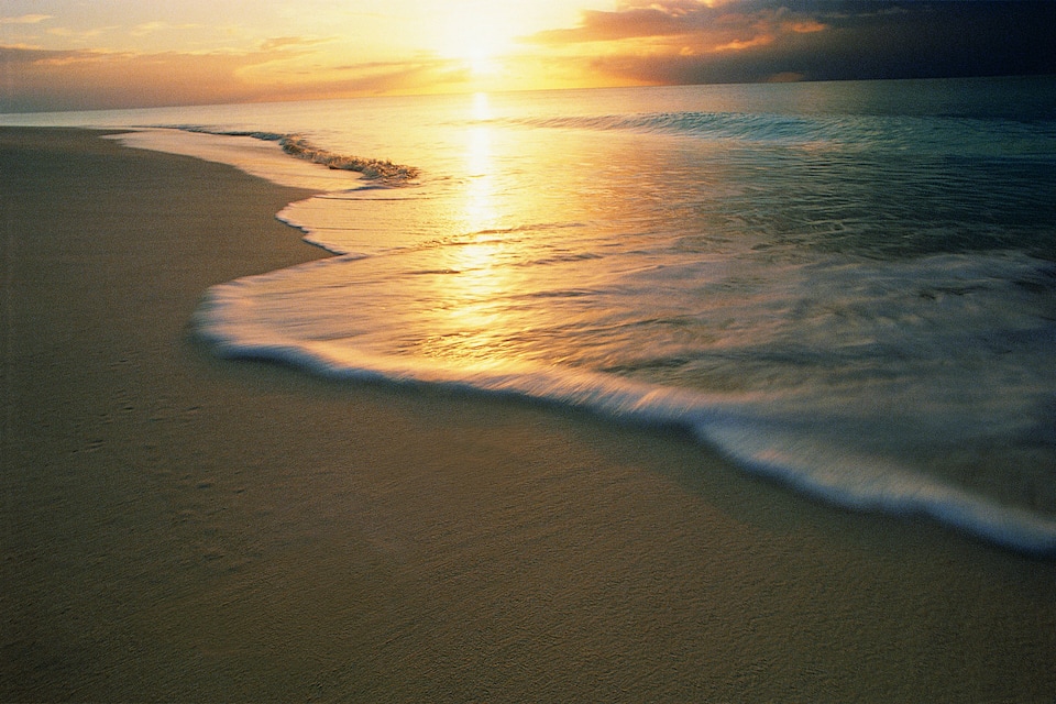 A beach with waves at sunset.