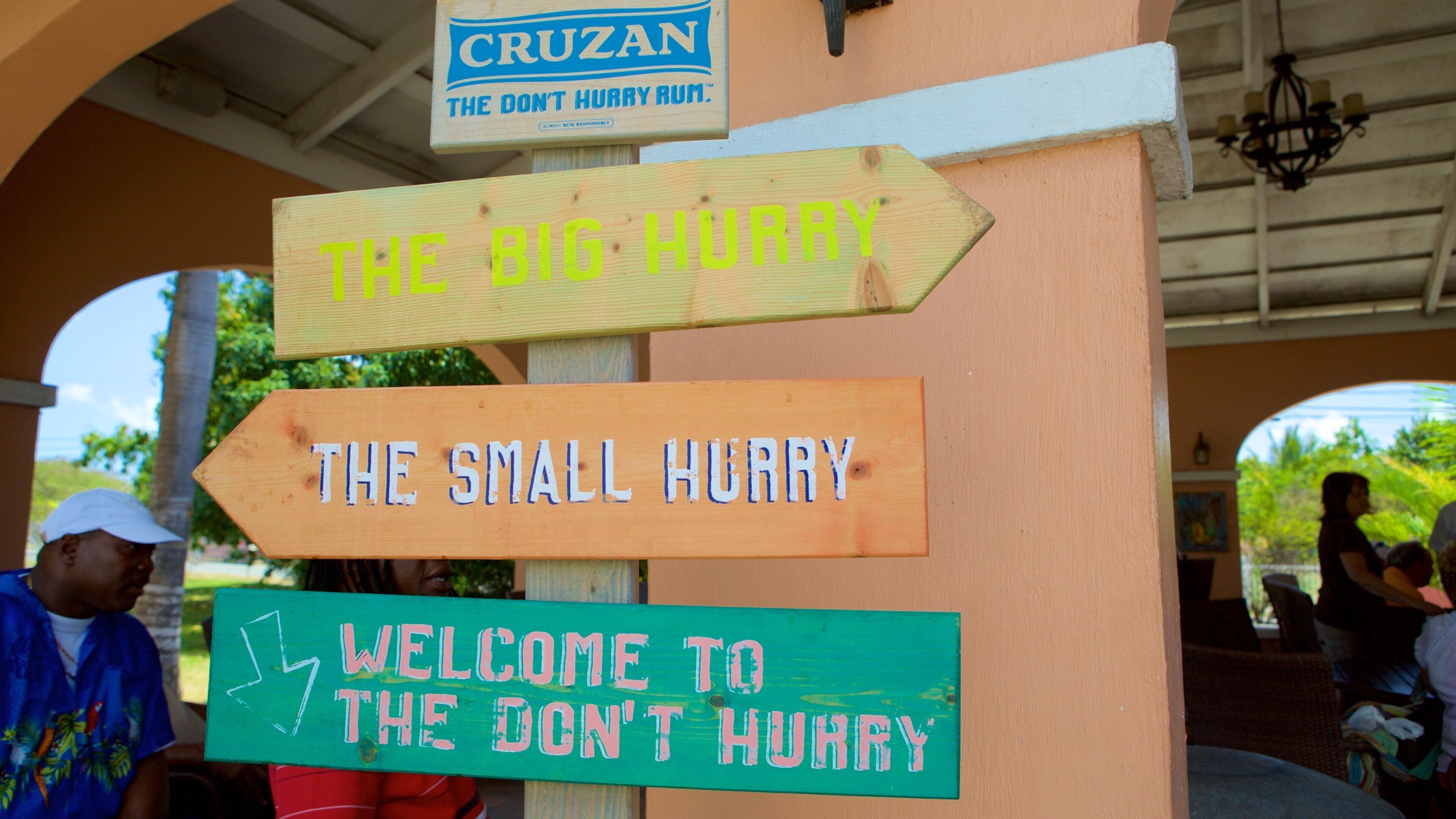 A wooden signpost with directional signs and a 'Welcome to the Don't Hurry' sign.