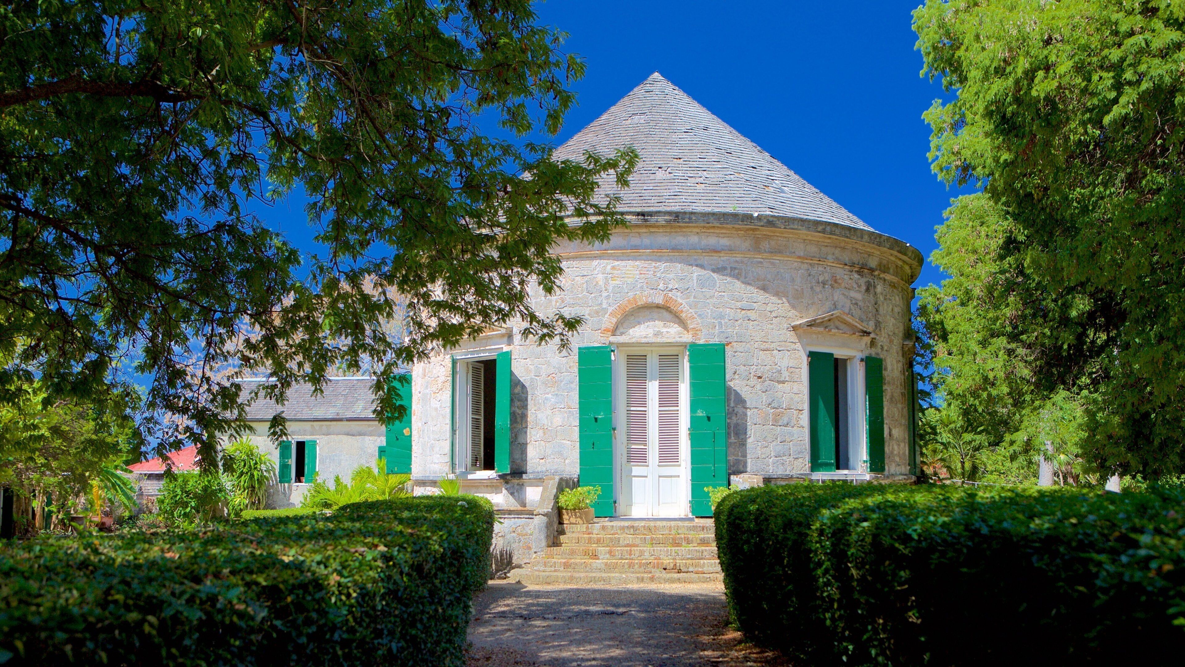 A stone building with a conical roof, green shutters, and a pathway leading to it.