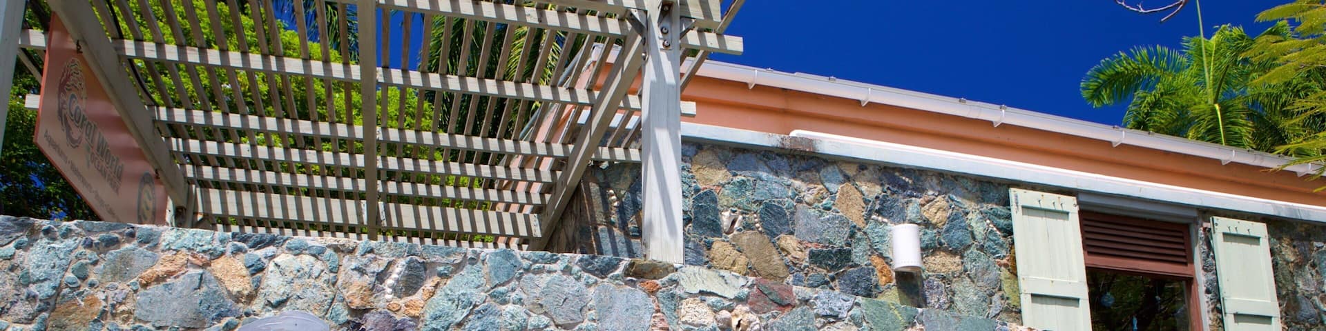 A stone wall with a sign that reads "Coral World" and a wooden pergola structure above it.