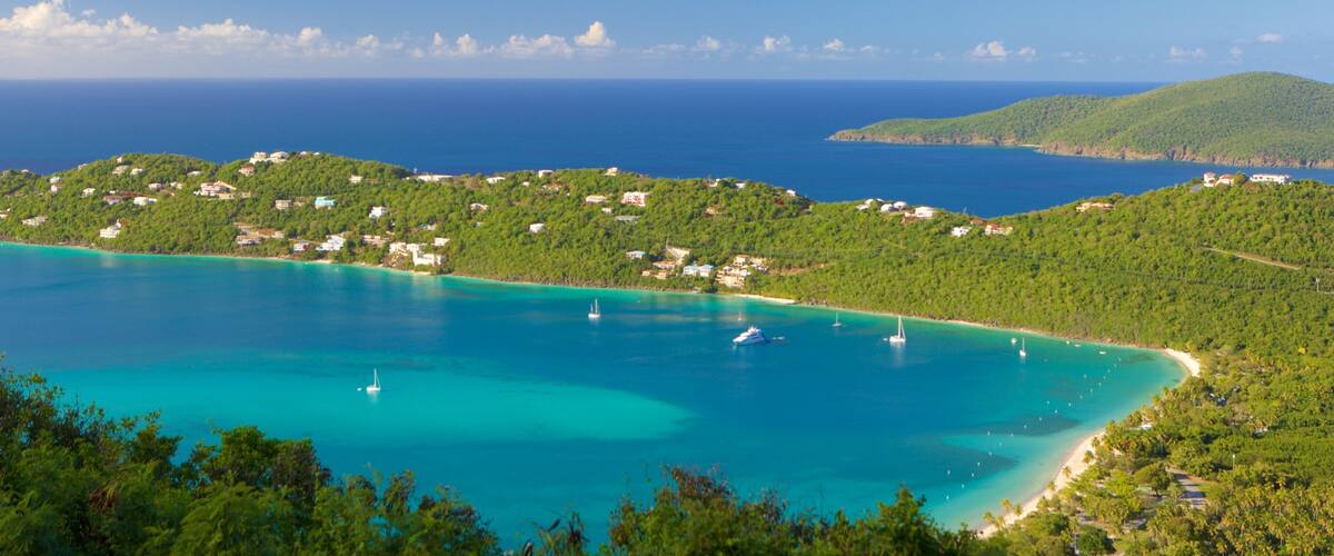 A coastal landscape with turquoise waters, green hills, and scattered buildings.