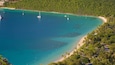 Une zone côtière aux eaux turquoise, avec une plage de sable fin et une végétation luxuriante.