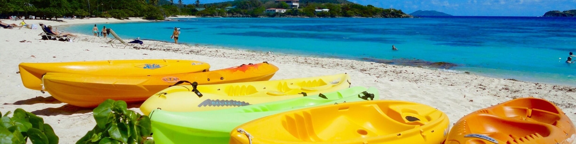 A beach with kayaks and a clear blue sea.