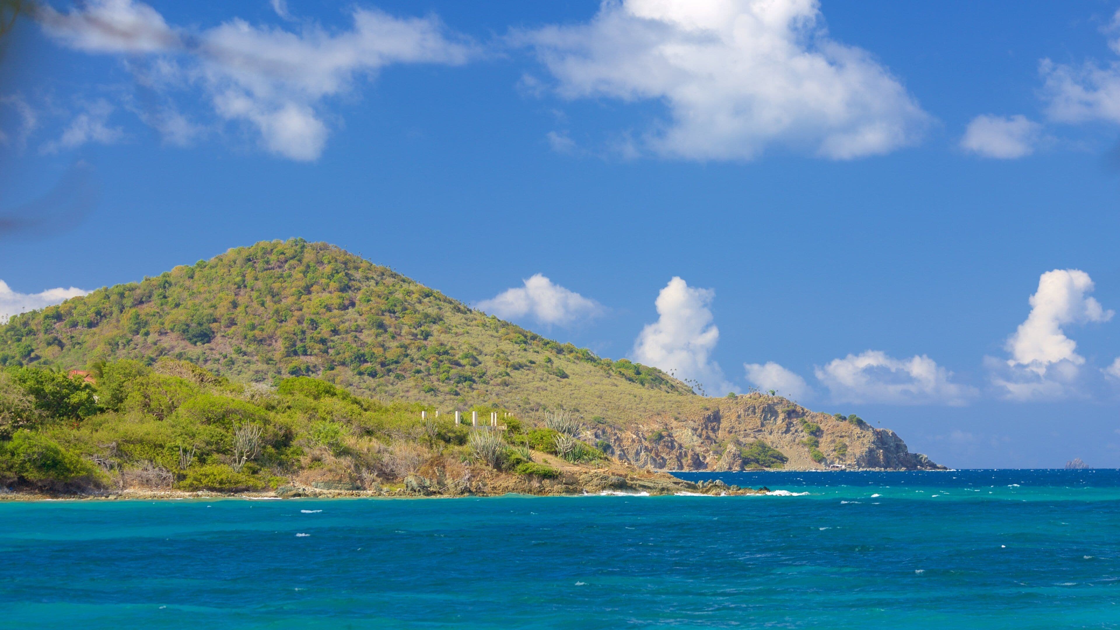 Una colina verde con cielo azul turquesa y mar turquesa.